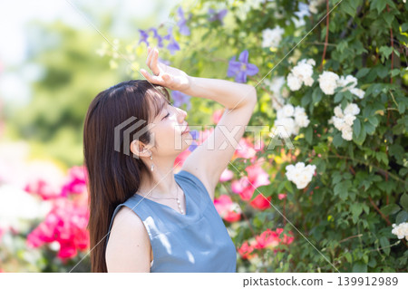 A woman enjoying a rose garden in early summer. A woman enjoying a rose garden in early summer. 139912989