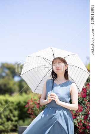 A woman enjoying a rose garden in early summer. 139912992