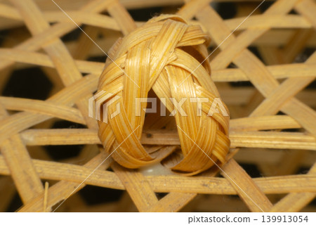 Closeup woven bamboo knot basket surface showing natural fiber pattern handcrafted material warm tone traditional texture detail Closeup woven bamboo knot basket surface showing natural fiber pattern handcrafted material warm tone traditional texture detail 139913054