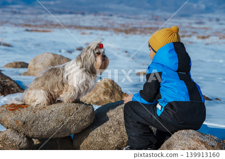 Child with shih tzu dog looking at each other on winter landscape background 139913160
