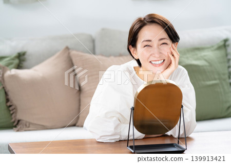 A woman looking at a mirror and smiling A woman looking at a mirror and smiling 139913421