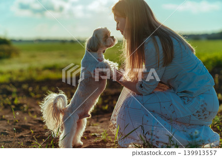 Young woman hugging a shih tzu dog in a field 139913557
