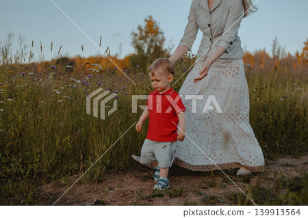 Mother and her small child walking in a field 139913564