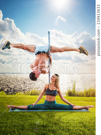 Young couple of pole dancers training on lake shore, creative concept Young couple of pole dancers training on lake shore, creative concept 139913633