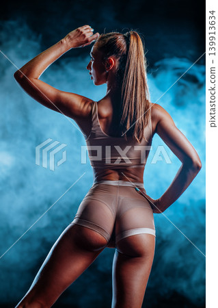 Young sexy slim fitness woman back view on dark smoke background 139913634