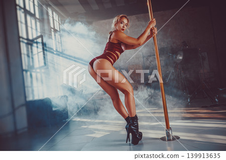 Young woman pole dancer in room with smoke at sunny day Young woman pole dancer in room with smoke at sunny day 139913635