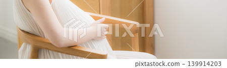 A Japanese pregnant woman with her hand on her stomach sits with a smile, representing a maternity lifestyle image. (Image: No face shown on banner) A Japanese pregnant woman with her hand on her stomach sits with a smile, representing a maternity lifestyle image. (Image: No face shown on banner) 139914203