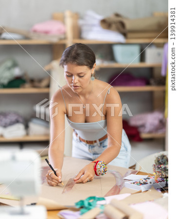Young fashion designer drawing patterns on paper 139914381