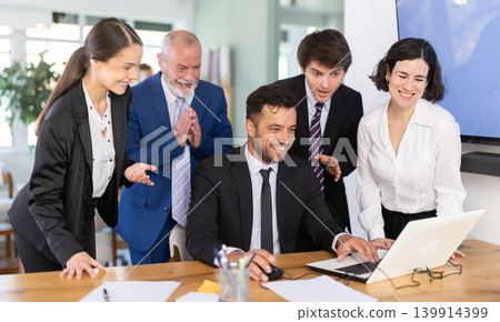Group of business people discuss business strategies and planning work together, everyone looking at laptop by man and laughing in corporate office Group of business people discuss business strategies and planning work together, everyone looking at laptop by man and laughing in corporate office 139914399