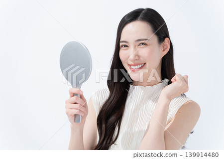 一位女士對著手鏡檢查自己的皮膚。 139914480