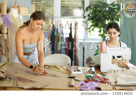 Female fashion designer drafting patterns in sewing workshop Female fashion designer drafting patterns in sewing workshop 139914605