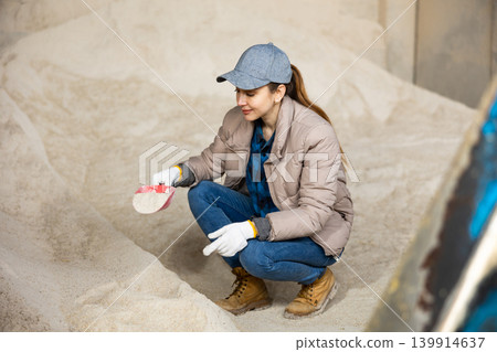 Woman farmer squatting at heap of corn flour 139914637
