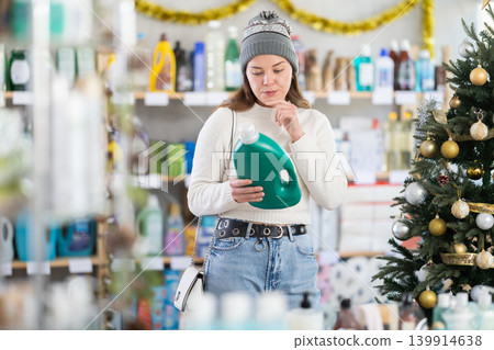 Young woman choosing detergent in New Year's supermarket Young woman choosing detergent in New Year's supermarket 139914638