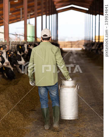 Rear view of male farmer with milk can Rear view of male farmer with milk can 139914641