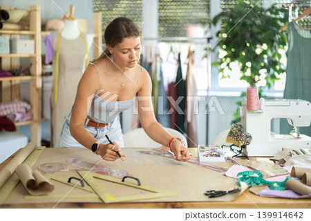 Female dress designer drawing patterns for garment using curve ruler 139914642