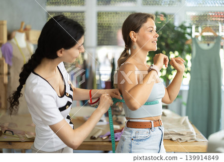 dressmaker takes measurements from the client dressmaker takes measurements from the client 139914849