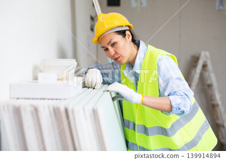 Female worker checking panels at renovating object Female worker checking panels at renovating object 139914894