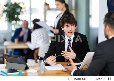 Consultant of a modern bank office tells a man about deposits and savings accounts 139914911