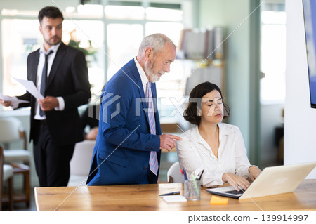 Female bank manager sitting at desk with elderly boss in front 139914997
