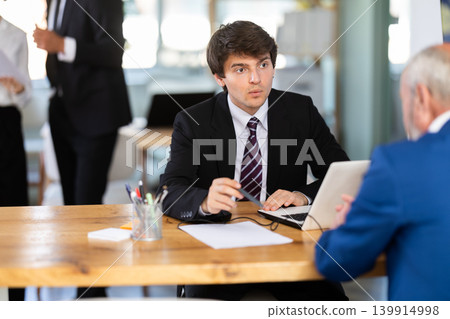 Bank manager talking with elderly male client in office Bank manager talking with elderly male client in office 139914998