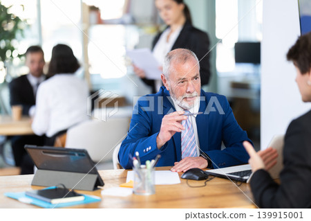 Bank manager talking with young male client in office 139915001