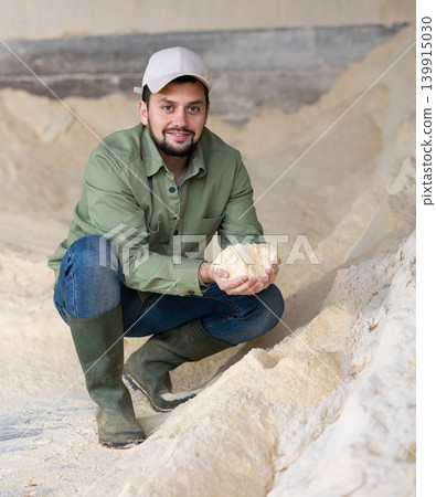 Young farmer checking quality of soy flour in livestock farm storage Young farmer checking quality of soy flour in livestock farm storage 139915030