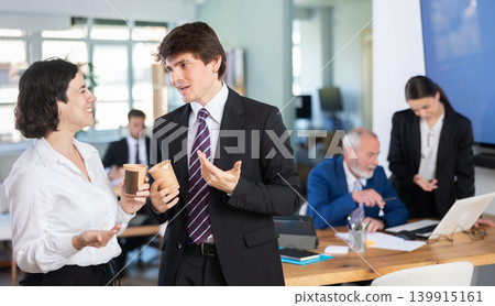 Smiling man and woman colleagues spending free time at coffee break in office 139915161