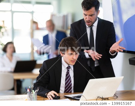 Adult man scolding young male colleague working on laptop 139915167