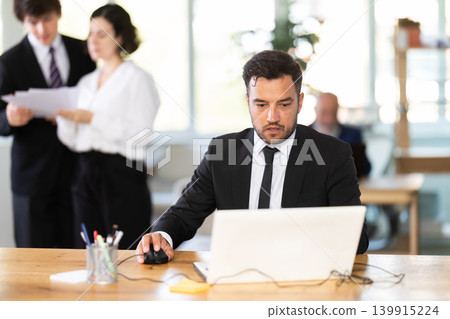 Business adult man concentrating on tasks while working at computer in office Business adult man concentrating on tasks while working at computer in office 139915224