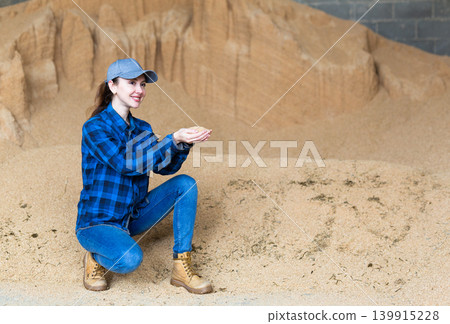 Woman agronomist squatting at bunch of soybean husk Woman agronomist squatting at bunch of soybean husk 139915228