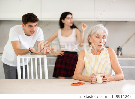 Adult children guy and girl are fighting with elderly woman mother. Adult children guy and girl are fighting with elderly woman mother. 139915242