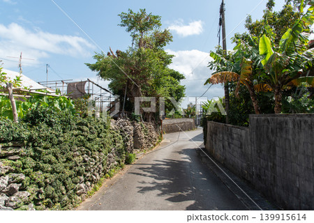 On a sunny day, the shadows of utility poles and houses fall on the road in the back alleys lined with old stone walls and concrete walls. On a sunny day, the shadows of utility poles and houses fall on the road in the back alleys lined with old stone walls and concrete walls. 139915614
