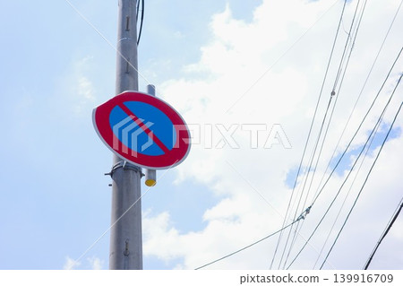 A distorted and deformed "No Parking" road sign against a blue sky. 139916709