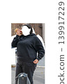 Woman in black tracksuit holding mobile phone, isolated on transparent background with transparent faceless area. Modern casual fashion PNG cutout for design and mockup use. High quality photo 139917229