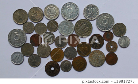 A collection of various antique Indonesian and international coins on a white background. A collection of various antique Indonesian and international coins on a white background. 139917273