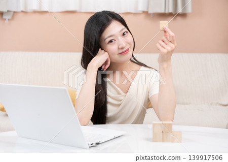 一位年輕女子暢想投資和財富累積：一台筆記型電腦和積木。 139917506