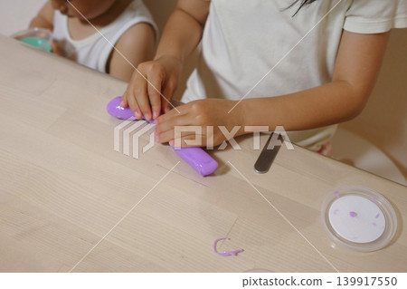 Two children in loungewear playing with slime at a table in their home. Two children in loungewear playing with slime at a table in their home. 139917550