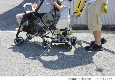 一位家長推著嬰兒車,帶著孩子去購物。 一位家長推著嬰兒車,帶著孩子去購物。 139917556