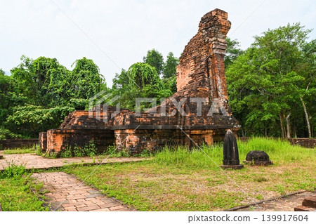 Ancient ruined red brick Hindu temple tower and stone monument at My Son Sanctuary historical archeological site in Vietnam Ancient ruined red brick Hindu temple tower and stone monument at My Son Sanctuary historical archeological site in Vietnam 139917604