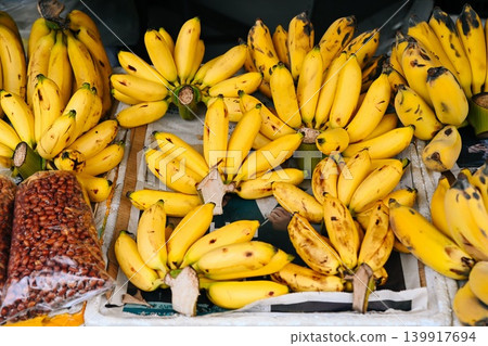 A close up view of sweet yellow Lady Finger bananas and roasted peanuts displayed at a traditional street fruit market stall in Hoi An Vietnam 139917694