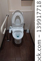 A clean Western-style toilet equipped with handrails and a heated bidet seat. 139917718