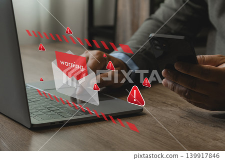 Person holding smartphone near laptop with phishing email warning icons and spam alert interface, representing cyber security risk, fake text message scam, online fraud, and data protection. 139917846
