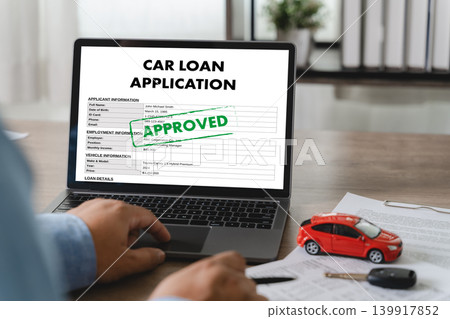 Customer reviewing approved car loan application on laptop with vehicle model, car key, and financial documents for auto financing, banking approval, credit verification, and loan process. Customer reviewing approved car loan application on laptop with vehicle model, car key, and financial documents for auto financing, banking approval, credit verification, and loan process. 139917852