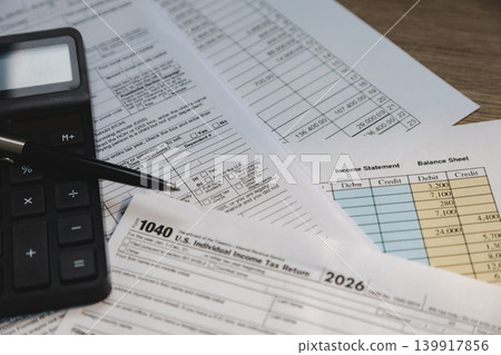 Income statement, tax paperwork, and calculator arranged for financial review, accounting preparation, bookkeeping process, and expense reporting workflow. Income statement, tax paperwork, and calculator arranged for financial review, accounting preparation, bookkeeping process, and expense reporting workflow. 139917856