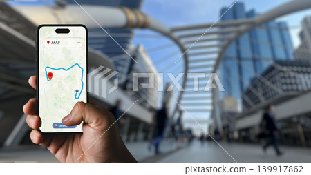 Hand holding smartphone displaying GPS map route in modern urban street environment, suitable for mobile navigation, destination tracking, location connection, and digital map application concepts. 139917862