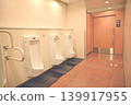 A clean men's restroom in a commercial facility, equipped with handrails and automatic flushing. 139917955