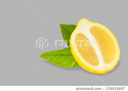 Lemon half with green leaves on a gray surface in bright light Lemon half with green leaves on a gray surface in bright light 139918097