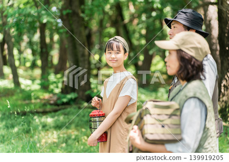 一個女孩和她的家人帶著露營裝備，準備戶外活動。 139919205