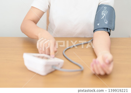 woman checking Blood pressure by Blood pressure monitor with Cuff. Systolic, SYS, Diastolic, DIA, Pulse, Hypertension, Hypotension, Heart rate, Cardiovascular Disease and May World hypertension day 139919221