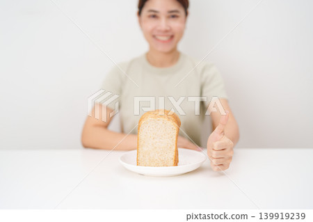 Happy smiling woman with whole wheat bread and thumbs up gesture. Weight loss, Dieting, Healthy eating, Calorie control, Fitness food, High fiber, Wellness, Lifestyle, Metabolism and Glycemic Index Happy smiling woman with whole wheat bread and thumbs up gesture. Weight loss, Dieting, Healthy eating, Calorie control, Fitness food, High fiber, Wellness, Lifestyle, Metabolism and Glycemic Index 139919239